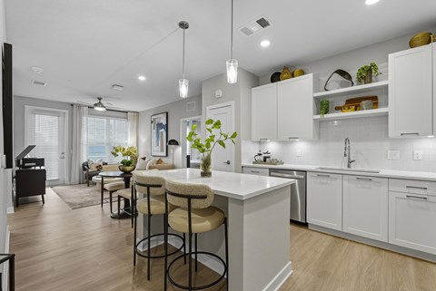 A kitchen with white cabinets and a bar area with stools.