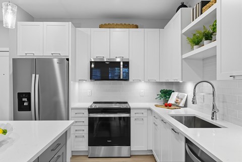 A modern kitchen with white cabinets and stainless steel appliances.