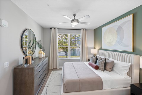 A bedroom with a large bed, a dresser, and a ceiling fan.
