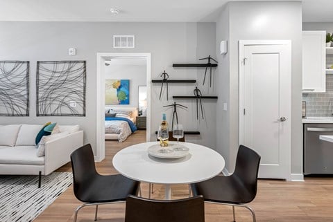 A modern dining room with a white table and black chairs.