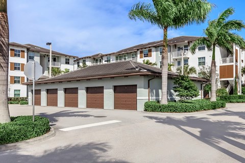 A row of houses with garages and palm trees in front.