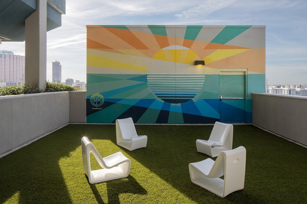 a terrace with lawn chairs and a mural on the wall