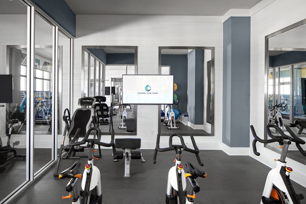 a gym with exercise equipment and a screen on the wall