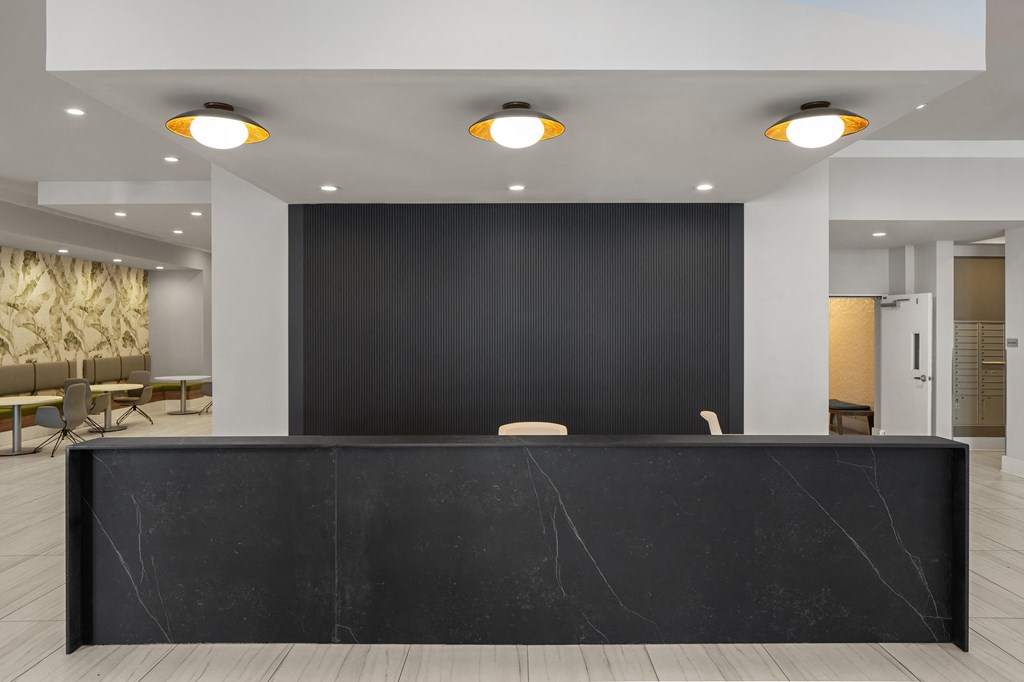 a large black reception desk in a lobby with three lights on the ceiling