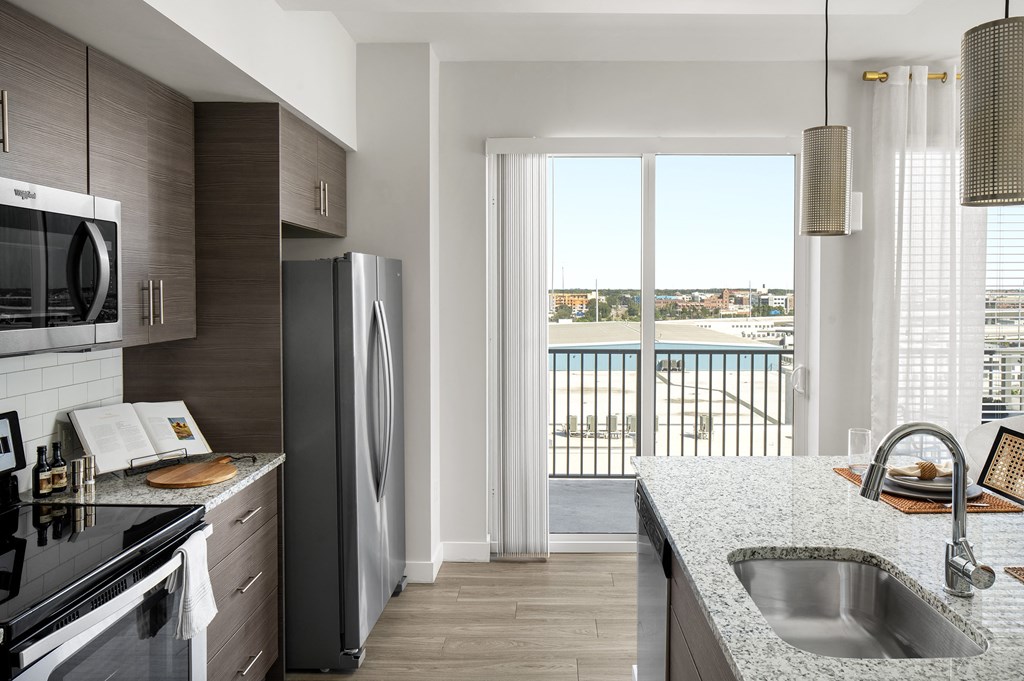 a kitchen with a sink and a refrigerator    and a balcony