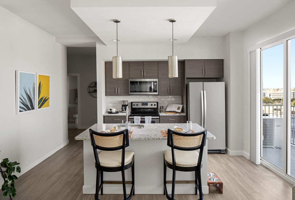 a kitchen with a island with three chairs and a refrigerator