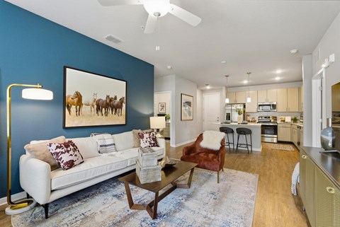 A living room with a white couch and a painting of horses on the wall.