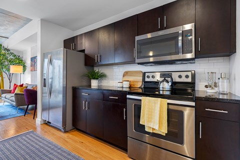 A modern kitchen with dark brown cabinets and stainless steel appliances.