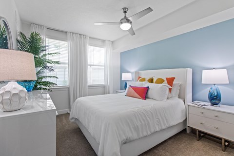 a bedroom with a white bed and a ceiling fan