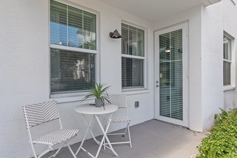 a patio with two chairs and a table with a potted plant