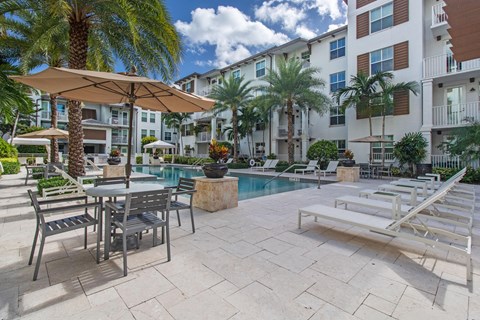a swimming pool with tables and umbrellas in front of a building