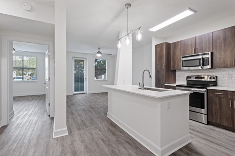 an open kitchen and living room with a large counter top and a sink