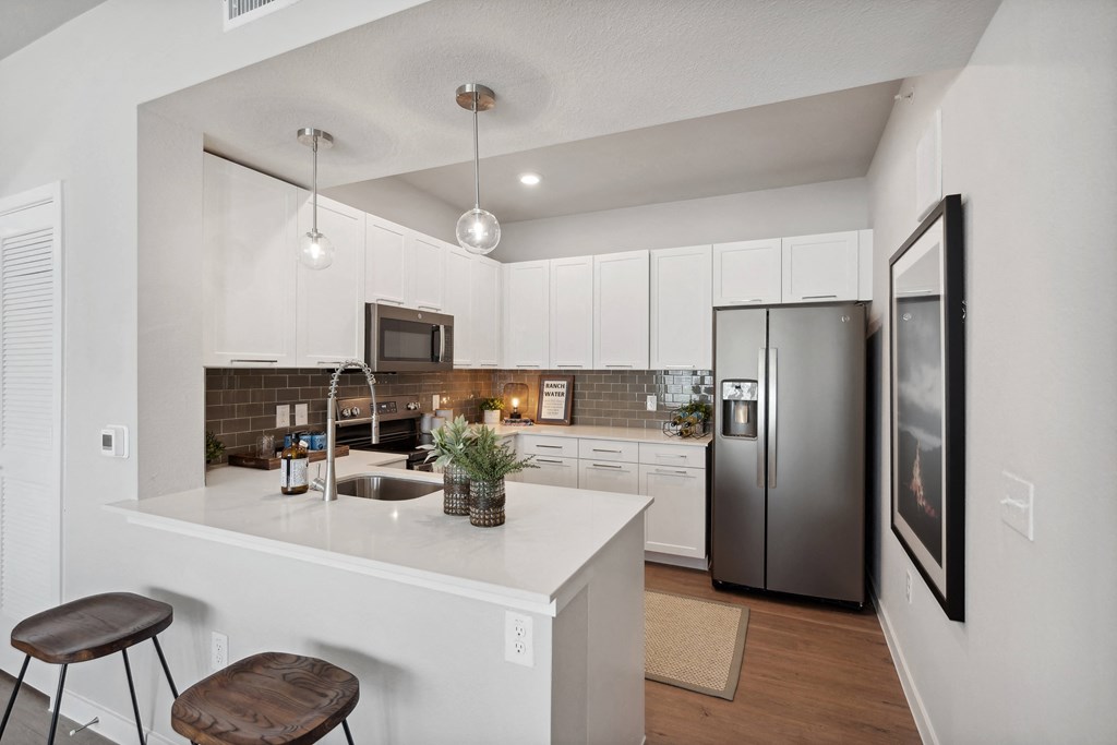 a kitchen with white cabinets and a stainless steel refrigerator