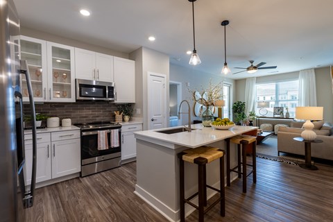 an open kitchen and living room with a large island and white cabinets