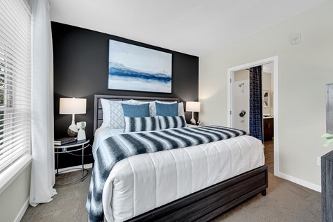 A bedroom with a large bed and a painting on the wall.