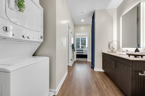 A white oven with a plant on top is in a kitchen with wooden floors.
