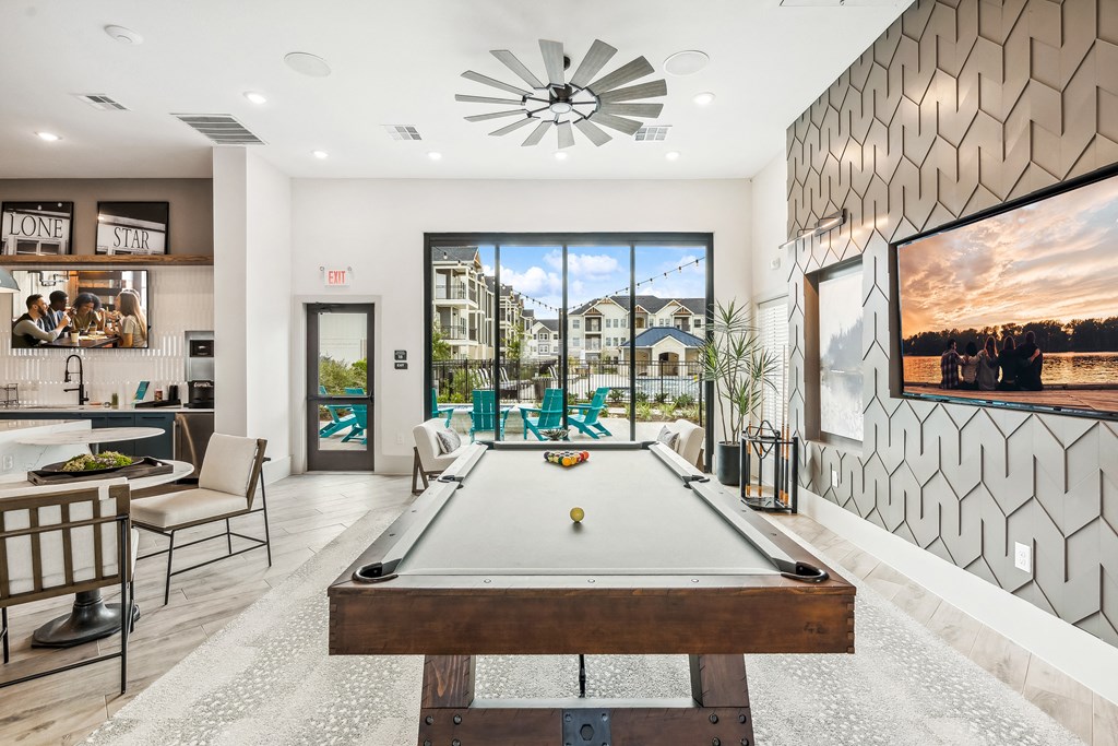 a pool table in the center of a living room with a view of a patio