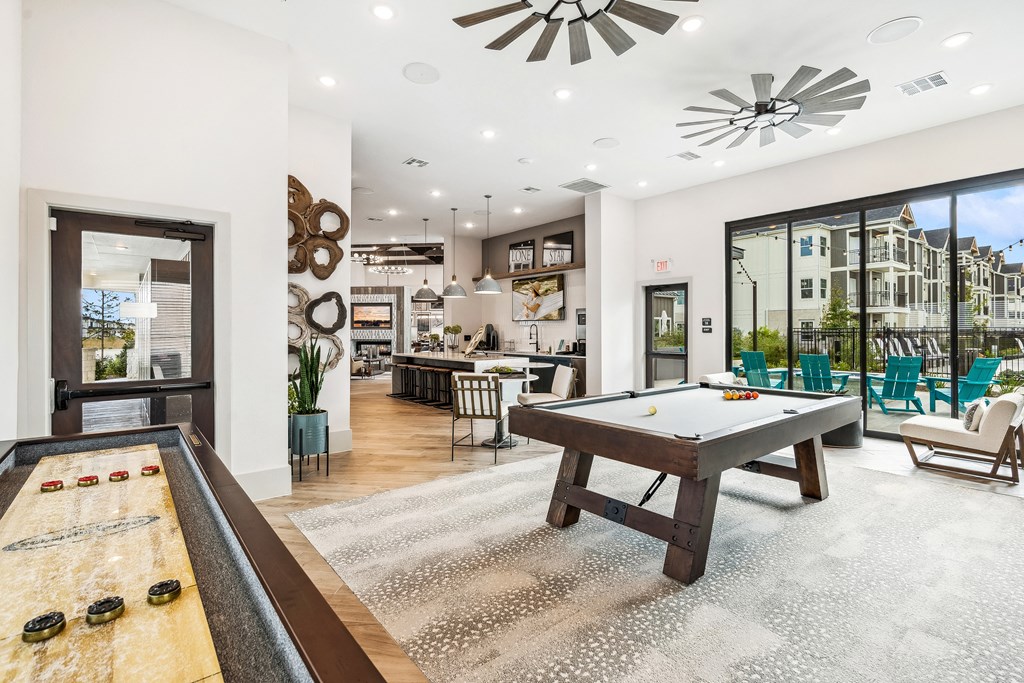 a game room with a shuffleboard table and a pool table