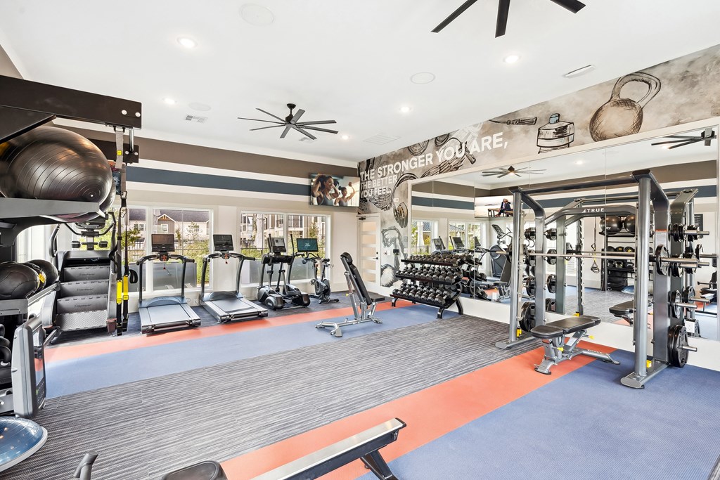 a gym with weights and cardio equipment and a ceiling fan