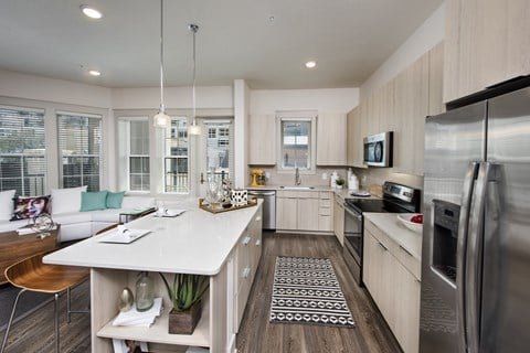 an open kitchen and living room with a large island and stainless steel appliances