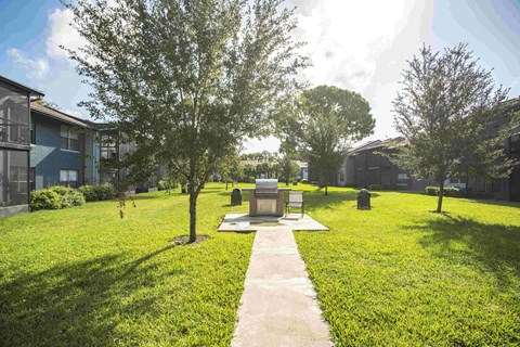 a park with grass and trees and a fire pit