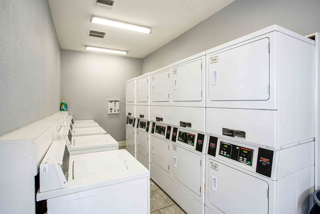 the laundry room is equipped with washers and dryers and plenty of white machines