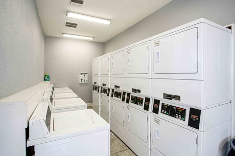 the laundry room is equipped with washers and dryers and plenty of white machines