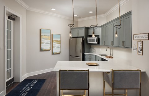 A kitchen with a white counter top and grey cabinets.