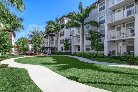 A sunny day at a residential complex with a walkway and palm trees.