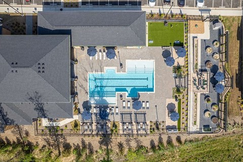 A large swimming pool is surrounded by a deck and lounge chairs.