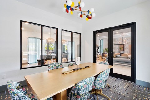 A dining room with a wooden table and chairs with a view of the outside.