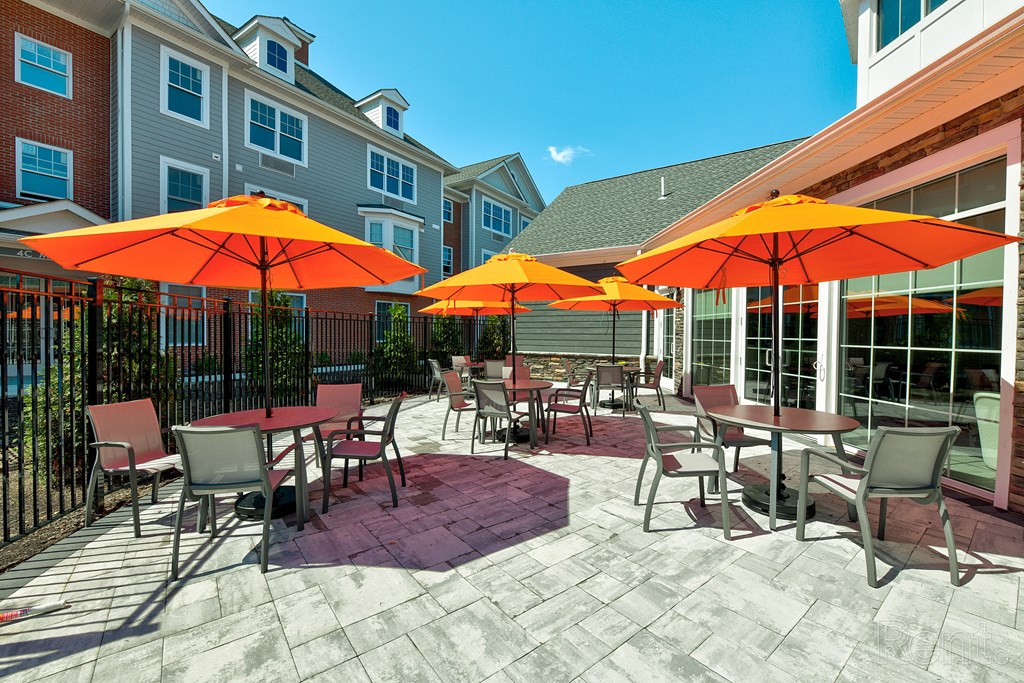 a patio with tables and chairs and umbrellas  at Solo at North Bergen, North Bergen, New Jersey