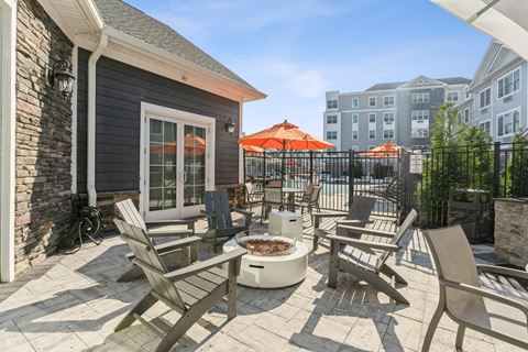 a patio with chairs and a fire pit and a building