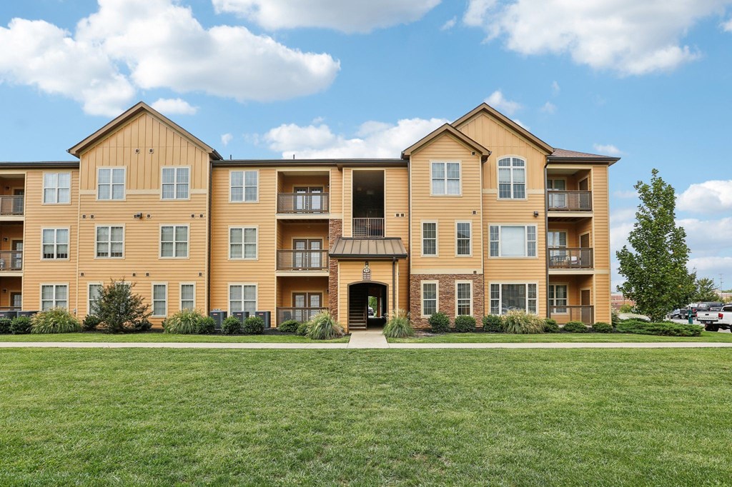 a large apartment building with a green lawn