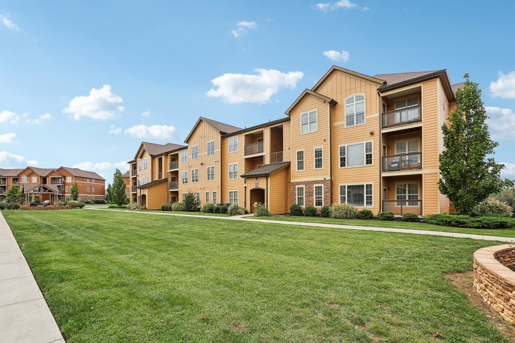 the view of an apartment building with a green lawn