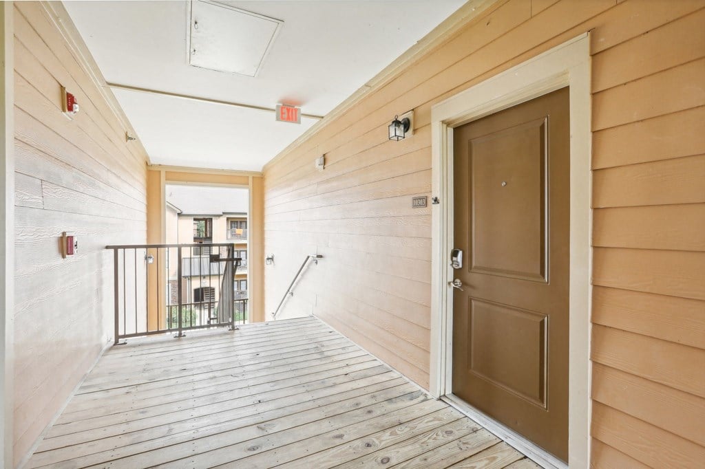 the entrance to a condo with a wooden floor and a brown door