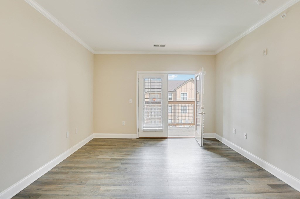 an empty living room with a door to a balcony