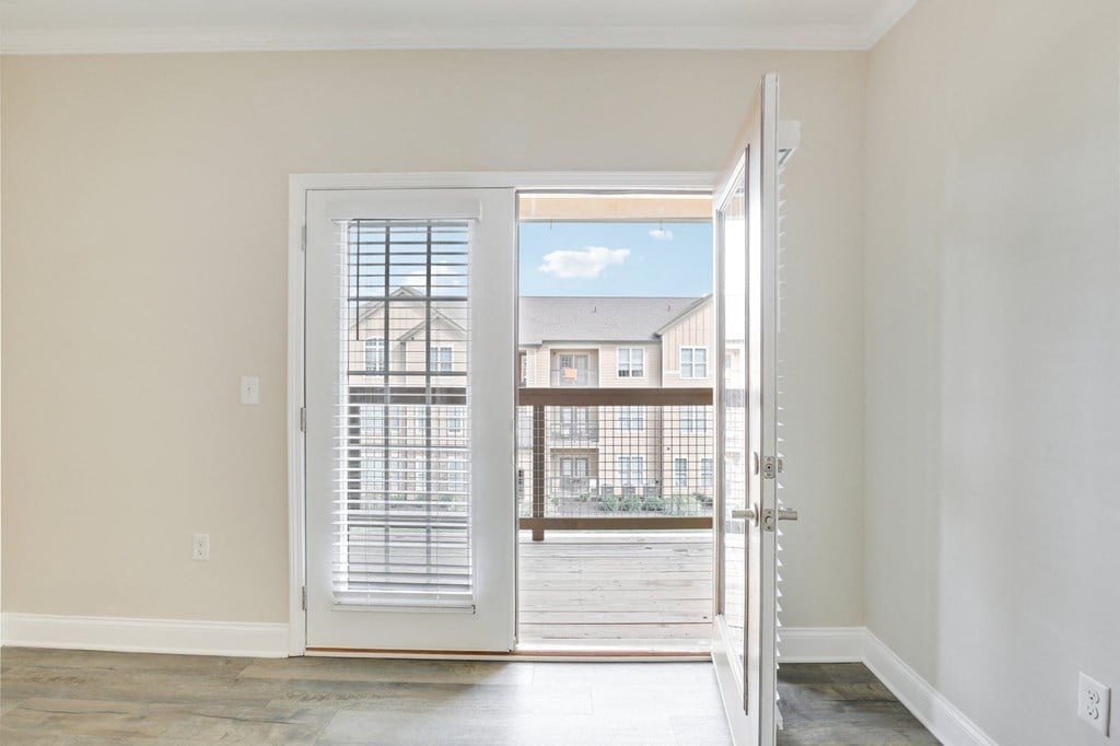 an empty living room with a door open to a balcony