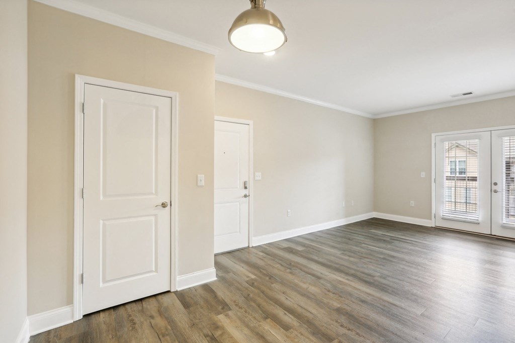an empty living room with white doors and a window