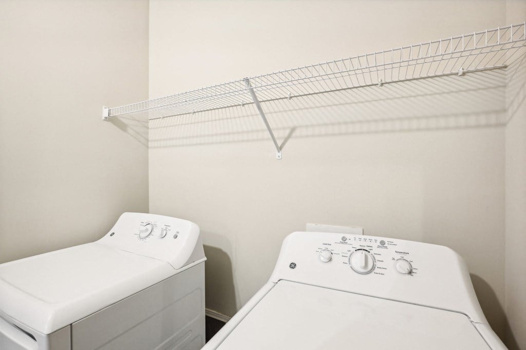 a washer and dryer in a laundry room with a rack on the wall