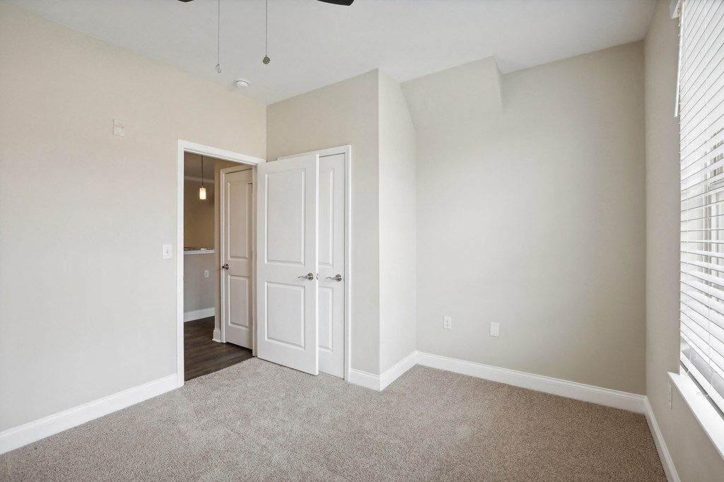 an empty bedroom with white doors and a door to a closet