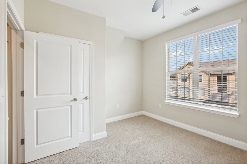 an empty bedroom with a large window and a white door