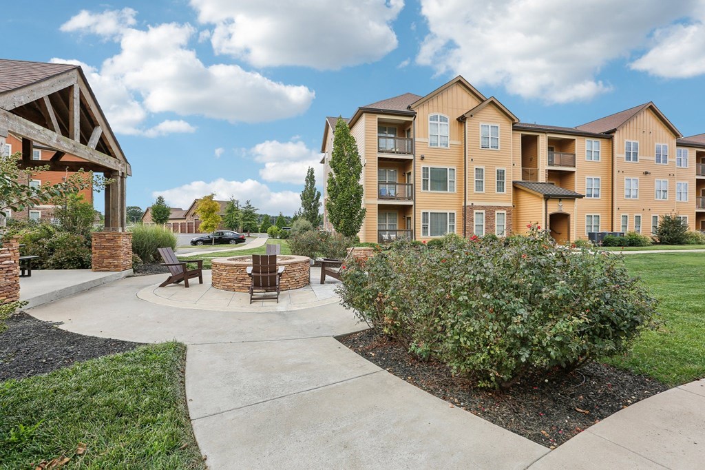 an outdoor patio with a fire pit in front of an apartment building