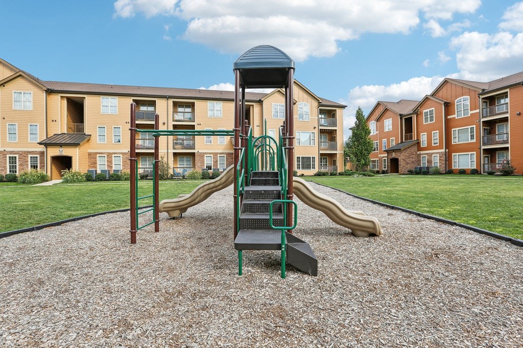 a playground with slides in front of an apartment complex