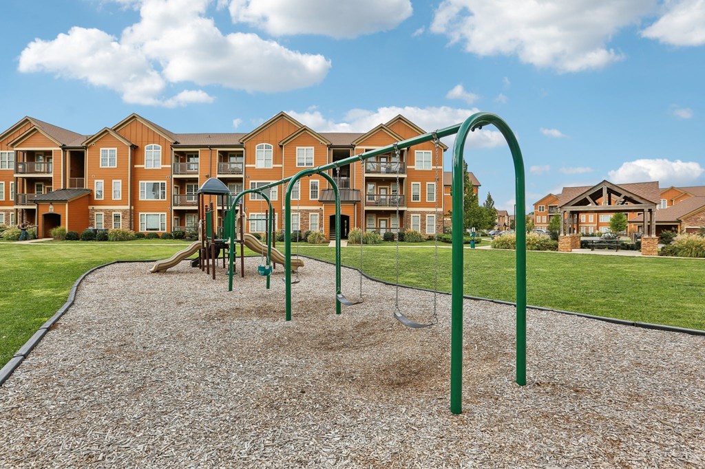 an empty playground with an apartment building in the background