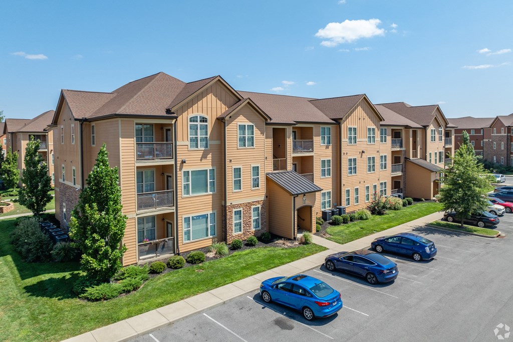 an apartment building with cars parked in a parking lot