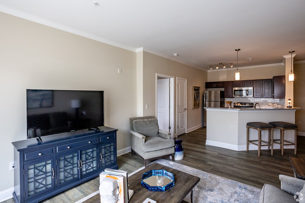 a living room with a tv and a kitchen with a bar and a table