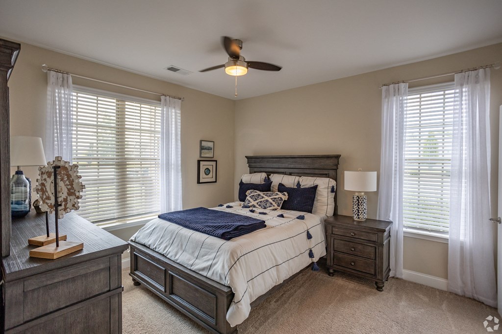 a bedroom with a bed and two windows and a ceiling fan