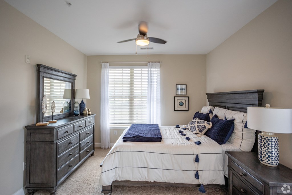 a bedroom with a bed and dresser and a ceiling fan