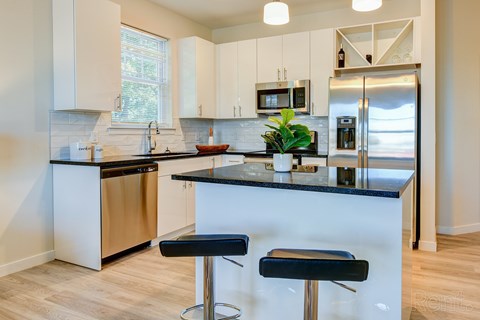 A kitchen with a black counter top and white cabinets.